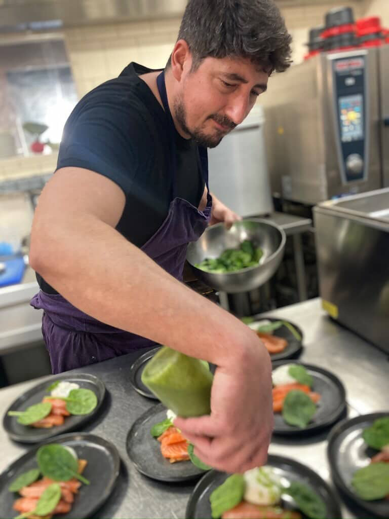 Chef en cuisine préparant des plats dans un restaurant à Plancoët